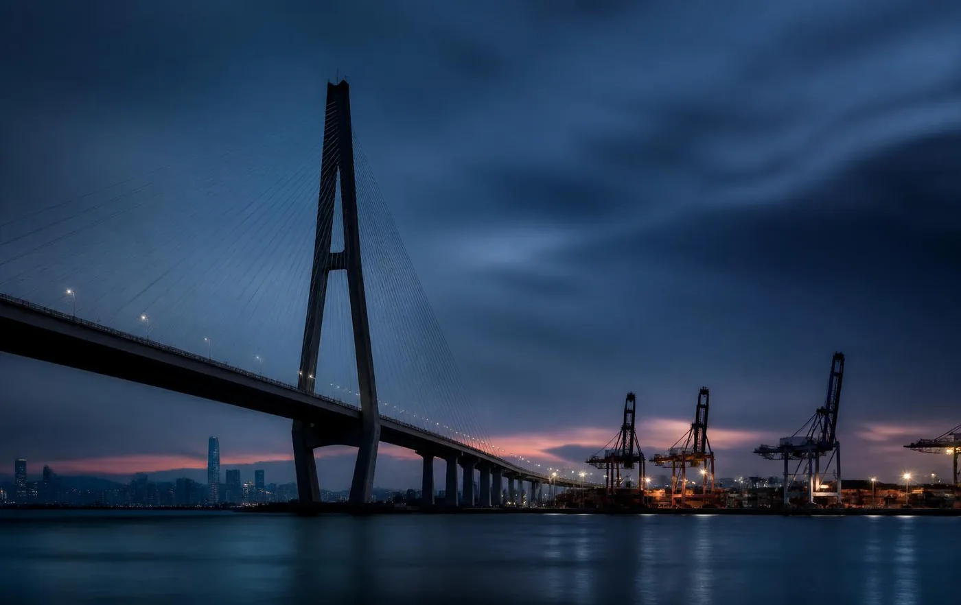 Cable-stayed bridge and container port infrastructure at dusk